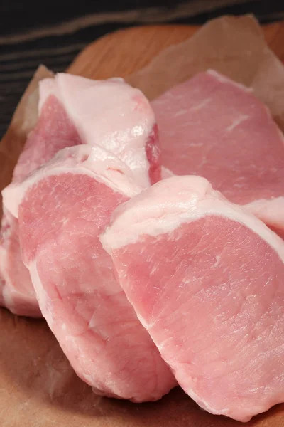 Bistecche fresche di maiale crudo su un tagliere su carta. Primo piano — Foto Stock