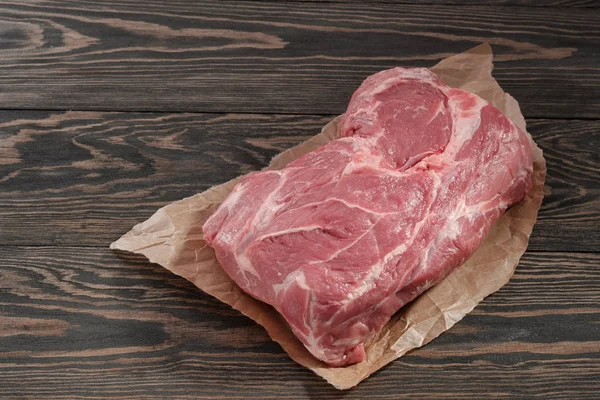 A piece of raw pork neck on paper. Pork tenderloin on paper on a dark background — Stock Photo, Image