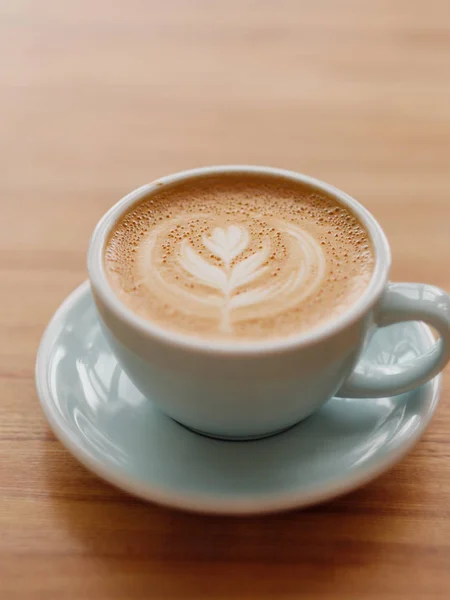 En kopp kaffe i en vacker blå kopp på ett woodern bord på caféet. — Stockfoto
