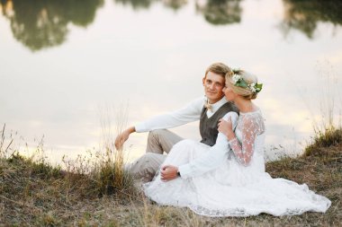 Fon karşı düğün kıyafetleri içinde birkaç göl günbatımı, gelin ve damat at. 