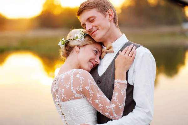 Пара у весільному вбранні на тлі озера на заході сонця, нареченого і нареченого . — стокове фото