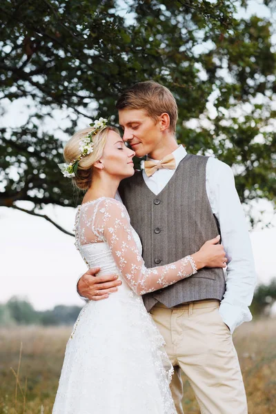 Bruden och brudgummen står på bakgrunden av trädet, efter vigseln. Nygifta leende, de är glada. Foto i varma toner. Stänga det.. — Stockfoto