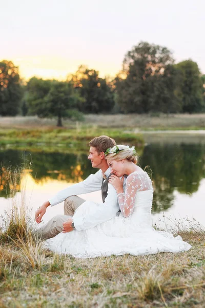 Szczęśliwa para w ślub stroje na tle jezioro o zachodzie słońca, Narzeczeni. — Zdjęcie stockowe