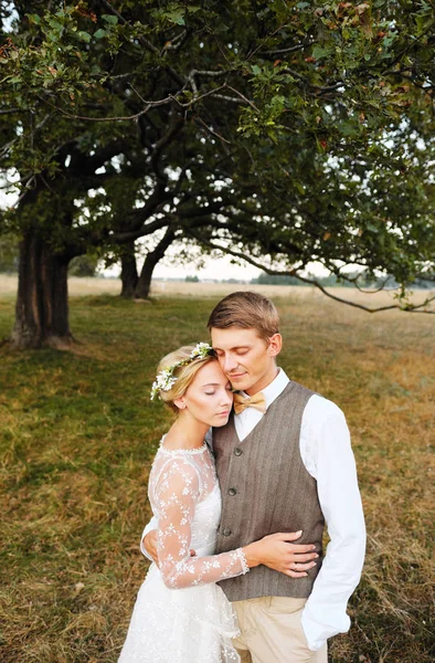 신부와 신랑 결혼식 후 나무의 배경에 서 있다. 신혼 부부는 웃 고, 그들은 행복 하다. — 스톡 사진