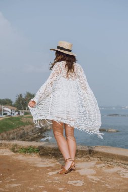 Kız şapka ve hafif beyaz giyim okyanusun yürüyüş
