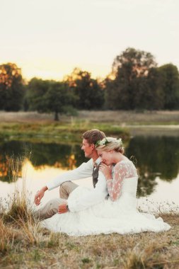 Göl günbatımı, gelin ve damat, düğün kıyafetleri fon karşı içinde mutlu çift. 