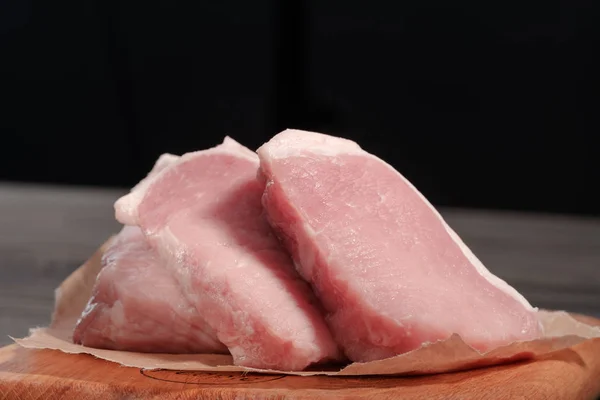 Bistecche fresche di maiale crudo su un tagliere su carta. Vista frontale — Foto Stock