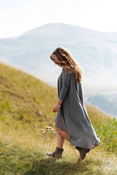 Una chica en un vestido largo está caminando por las montañas — Foto de Stock