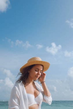Genç kadın bir beyaz mayo ve plaj güneşlenme şapka