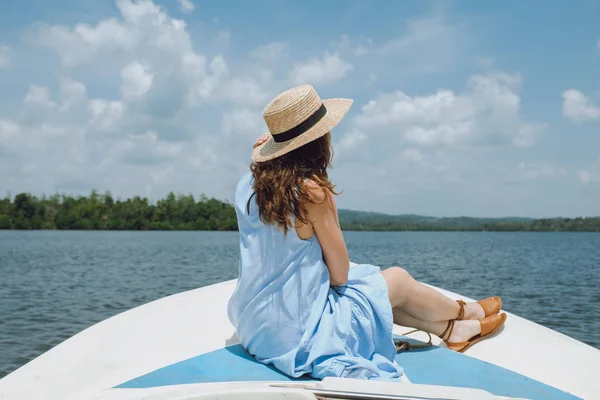 Jonge vrouw in een hoed zit aan de voorzijde van de zeilboot en bewondert de weergave — Stockfoto