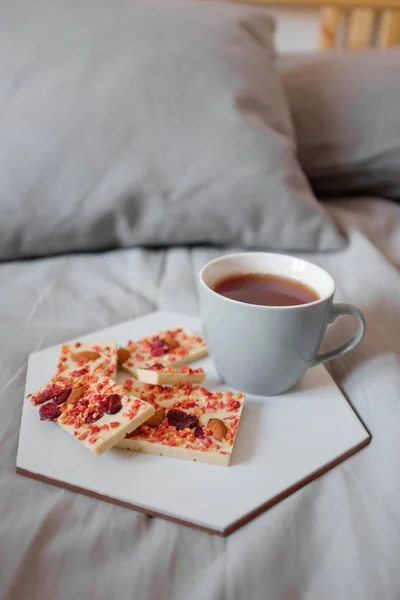 Pequeno-almoço na cama. Xícara de chá e chocolate branco — Fotografia de Stock