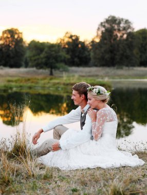 Göl günbatımı, gelin ve damat, düğün kıyafetleri fon karşı içinde mutlu çift. 