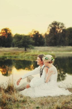 Göl günbatımı, gelin ve damat, düğün kıyafetleri fon karşı içinde mutlu çift. 