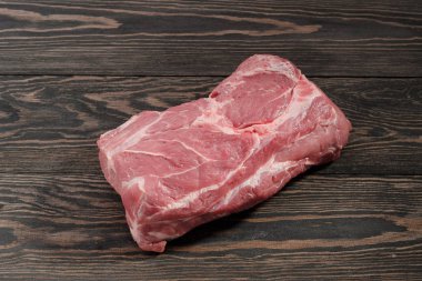 Çiğ domuz eti boyun parçası. Domuz eti bonfile karanlık bir arka plan üzerinde kağıt üzerinde