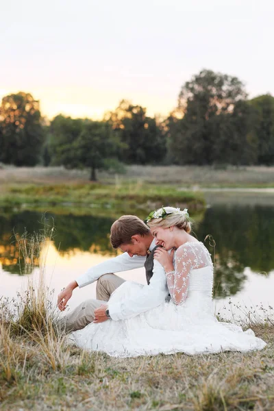 Fon karşı düğün kıyafetleri içinde birkaç göl günbatımı, gelin ve damat at. 