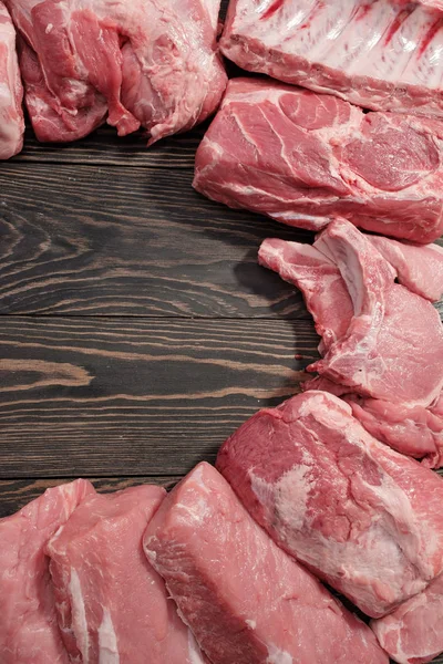 Různé syrové maso na dřevěné tmavé pozadí. Maketa — Stock fotografie