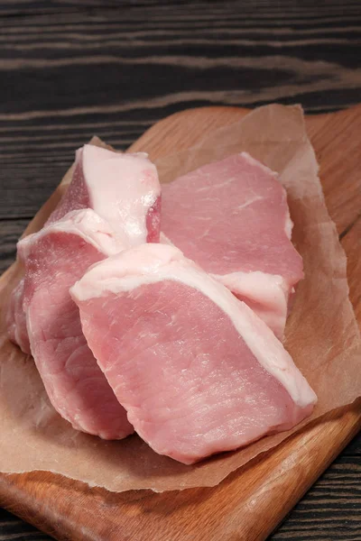 Bistecche fresche di maiale crudo su un tagliere su carta. Primo piano — Foto Stock