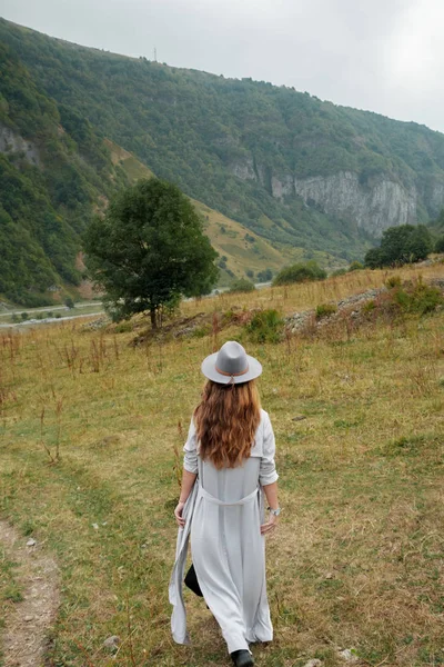 Una chica con sombrero camina cerca de las montañas — Foto de Stock