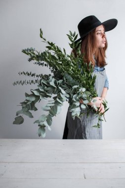 Çiçekçi bir buket yapar. İş süreci. Okaliptüs bir buket elinde tutan kadın