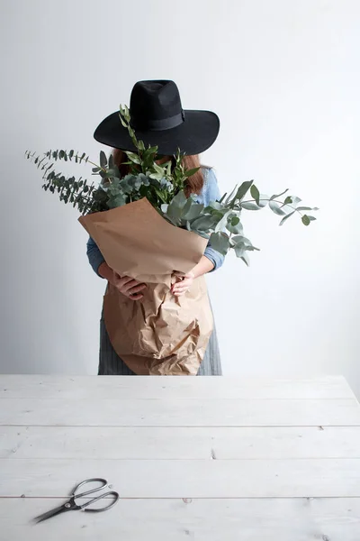 Дівчина з букетом евкаліпта в руках. дівчина-флорист з букетом евкаліпта в крафт-папері — стокове фото