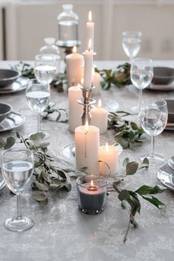 Düğün ya da şenlik masası. Tabaklar, şarap bardakları, mumlar ve çatal bıçak takımı.
