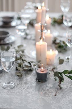 Düğün ya da şenlik masası. Tabaklar, şarap bardakları, mumlar ve çatal bıçak takımı.