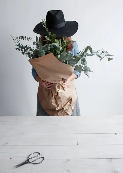 Дівчина з букетом евкаліпта в руках. дівчина-флорист з букетом евкаліпта в крафт-папері — стокове фото