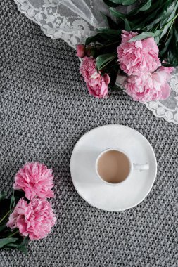 Bir fincan kahve ve gri arka plan üzerinde peonies