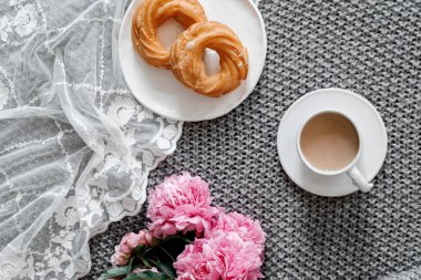 Bir fincan kahve ile tatlılar ve gri arka plan üzerinde peonies