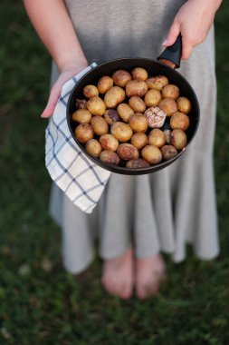 Kadın elleri tavayı kızarmış patatesle tutuyor.