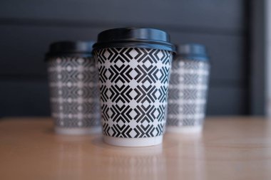 Ahşap arka planda plastik tek kullanımlık kahve fincanları