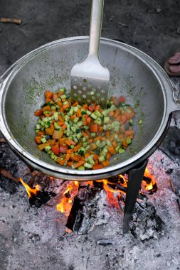 Tavada ateşte sebze kızartan insan görüntüsü.