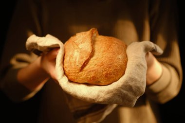 Bir somun taze ekmek tutan adamın kesilmiş görüntüsü.