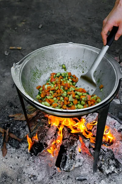 火の上で野菜を炒める男の姿を切り取った — ストック写真
