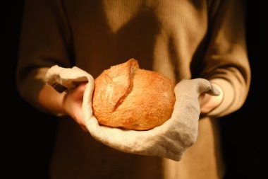 Bir somun taze ekmek tutan adamın kesilmiş görüntüsü.