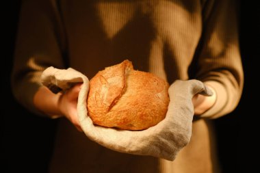 Bir somun taze ekmek tutan adamın kesilmiş görüntüsü.