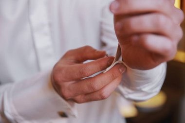 Erkek eli, kol düğmesini gömleğin koluna bağlıyor, yakın görüş.