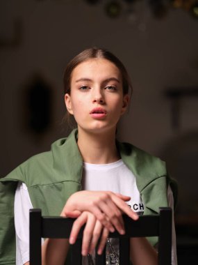 Genç hippi kadın odasındaki tahta sandalyede otururken poz veriyor. 