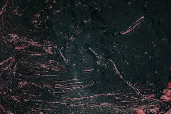 Black glossy mineral background with pink cracks and scratches .