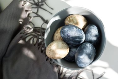 Kahverengi havluyla seramik kasede renkli yumurtalar.