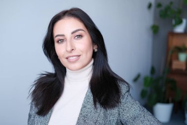 Gri takım elbiseli iş kadını stüdyoda poz veriyor.