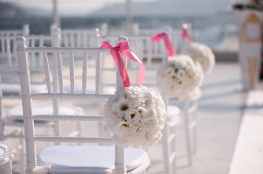 Decorated chairs prepared for festive wedding ceremony on pier by the sea