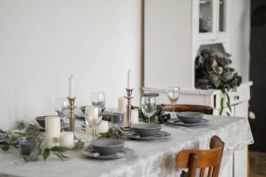 Dining table served for guests with festive candles and grey utensil