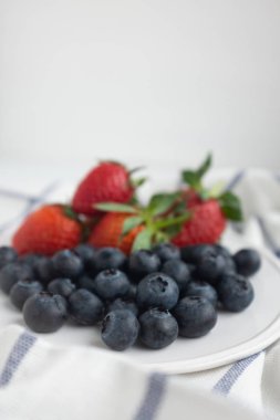 White plate with blueberries and strawberries