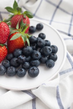 White plate with blueberries and strawberries