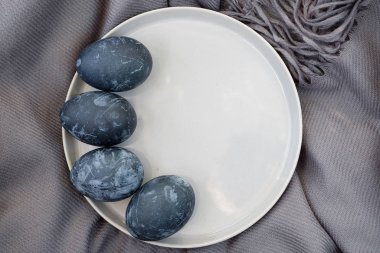 Kahverengi havluyla seramik kasede renkli yumurtalar.