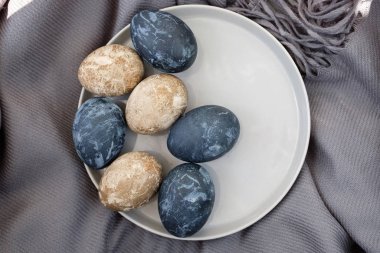 Kahverengi havluyla seramik kasede renkli yumurtalar.