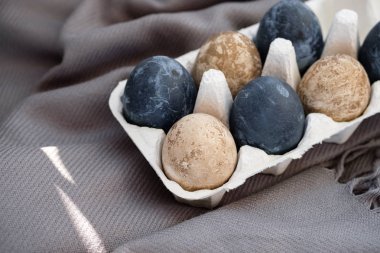 Masanın üzerindeki karton kutuda duran renkli yumurtalar.