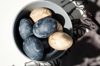 Kahverengi havluyla seramik kasede renkli yumurtalar.