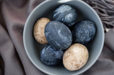 Kahverengi havluyla seramik kasede renkli yumurtalar.